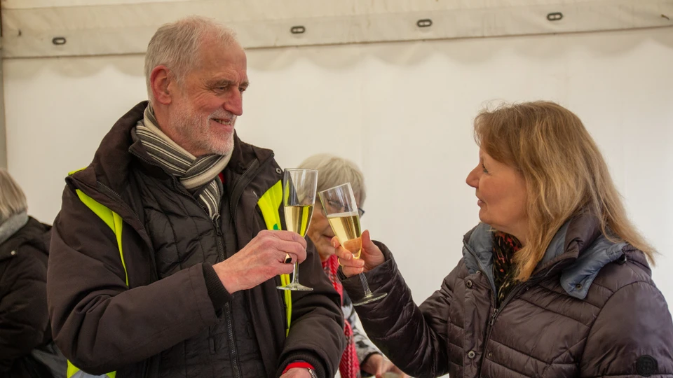 En mand og en kvinde klinker med champagneglas og hilser på hinanden.