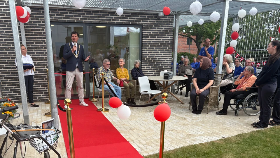 Mand står på rød løber med en mikrofon