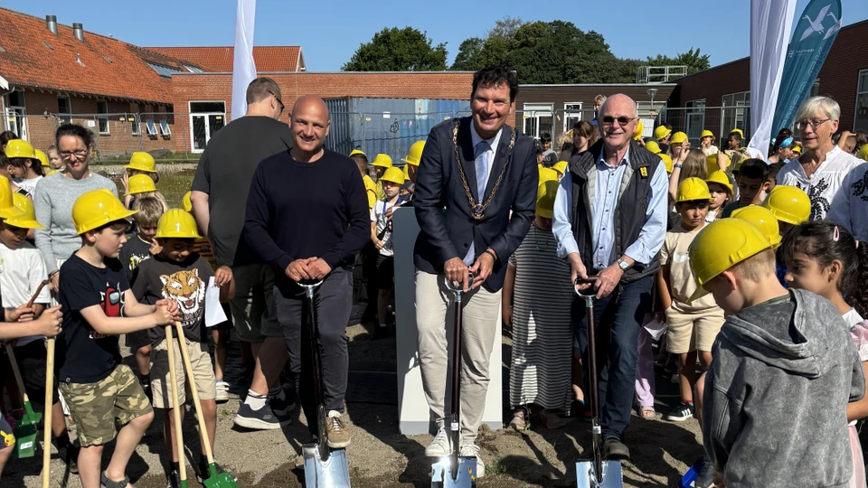 Tre mænd står i flok af børn med gule hjelme og spader i hænderne.