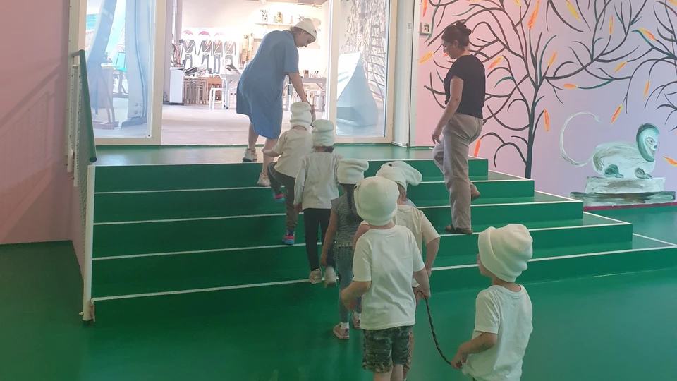 Børn på museum iført hvidt tøj, og som holder i en snor.