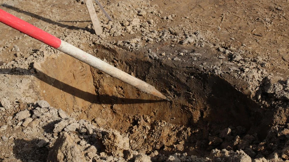 Et gravet hul, hvor et mørkere jordlag markerer, at der har stået en stolpe her.