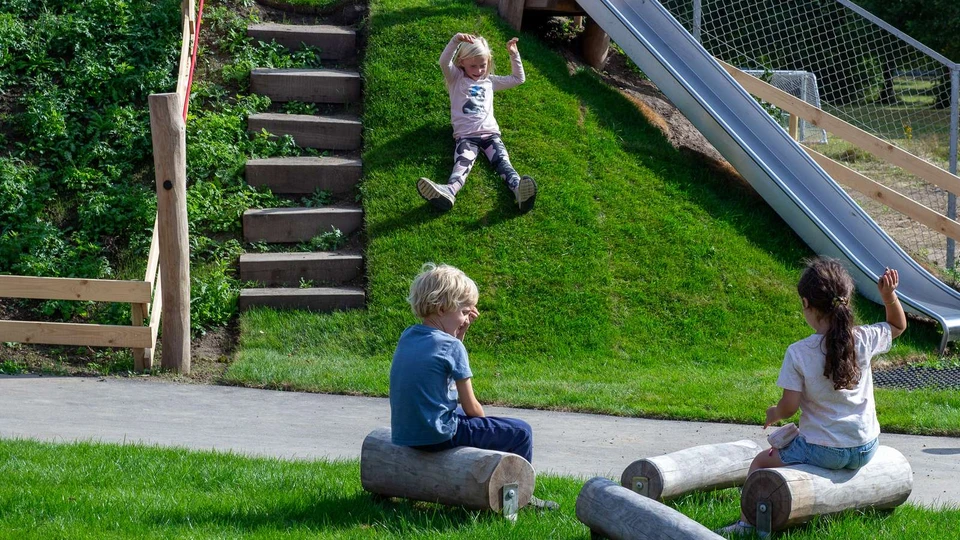 Børn på legeplads, en rutjser ned ad en bakke