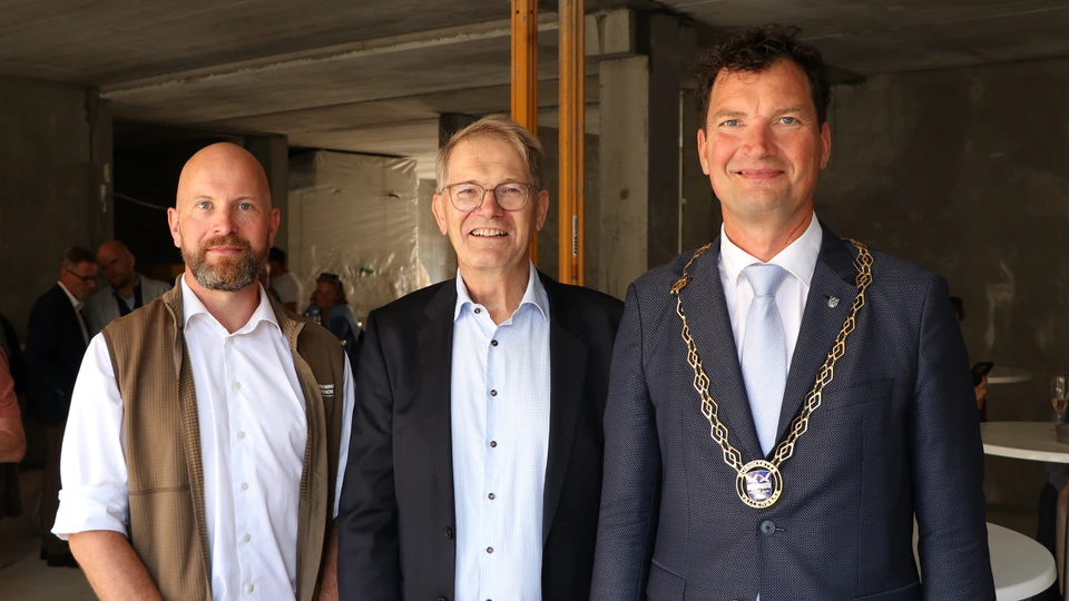 Tre mænd på række kigger i kameraet, i baggrunden rå betonvægge.