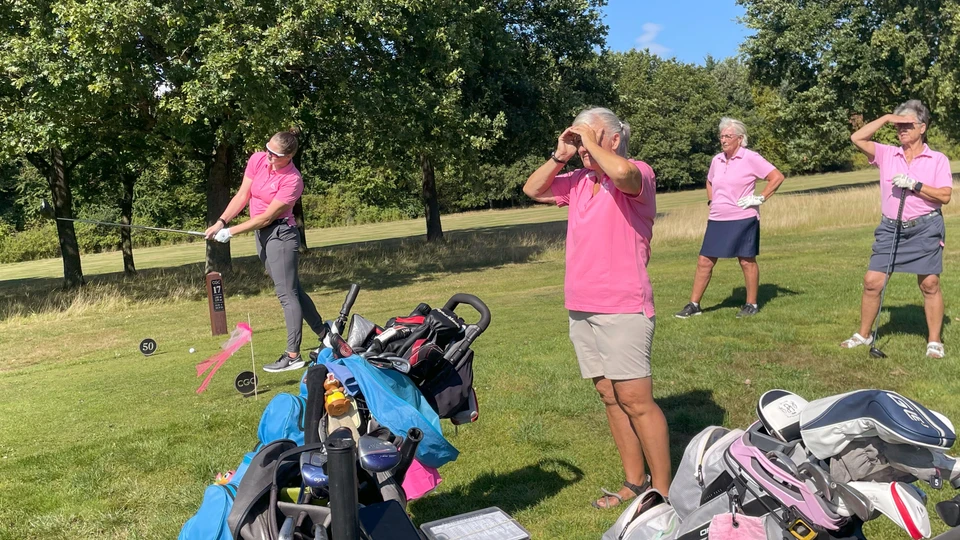Tre kvindelige golfspiller kigger ud mod det slag, som en fjerde spiller netop har sendt afsted.
