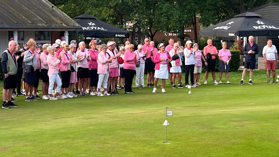En stor forsamling af mennesker i pink nuancer står på række og klapper