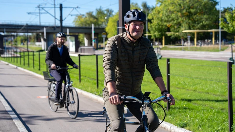 En mand kører på cykel med hjem, bag ham kører en anden cykelist.